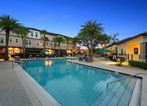 A swimming pool surrounded by palm trees and apartment buildings.