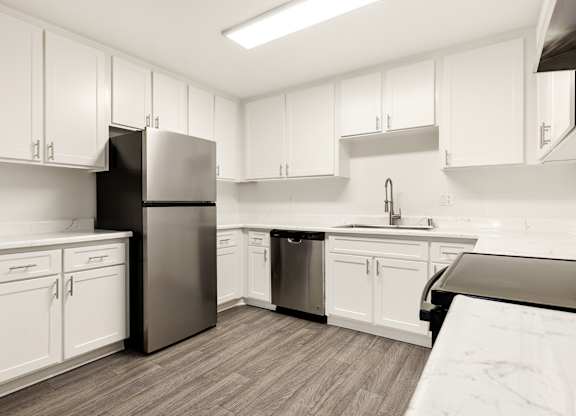 A kitchen with white cabinets and a black refrigerator.
