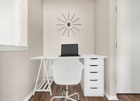 A white desk with a laptop and chair in front of a wall with a sunburst design.