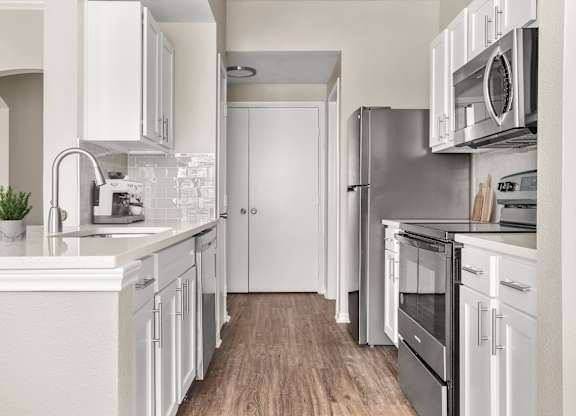 A modern kitchen with white cabinets and stainless steel appliances.