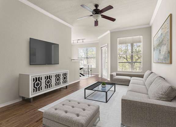 A living room with a grey couch, a glass coffee table, and a television on a cabinet.