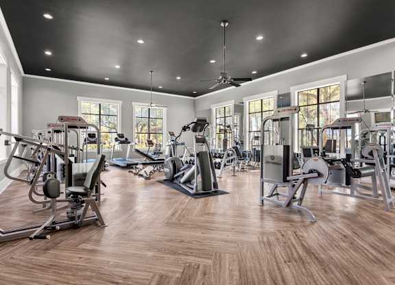 A gym with a variety of equipment and a wood floor.