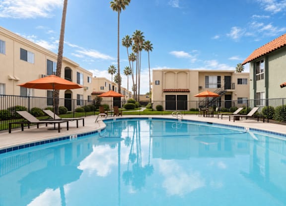 A swimming pool surrounded by palm trees and apartment buildings.