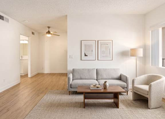 A living room with a grey couch, a brown coffee table, and a white chair.