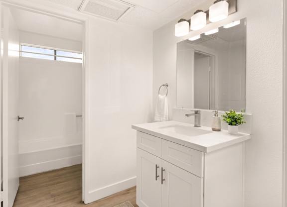 A white bathroom with a sink and mirror.