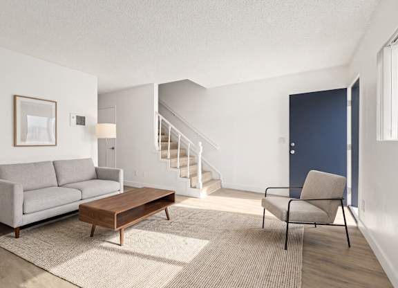 A living room with a grey couch, a brown coffee table, and a blue door.