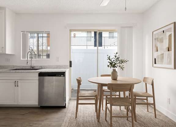 A kitchen with a table and chairs in front of a window.