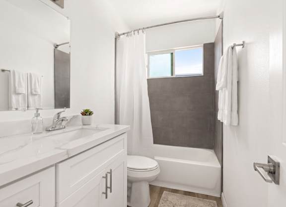 A white bathroom with a toilet, sink, and bathtub.
