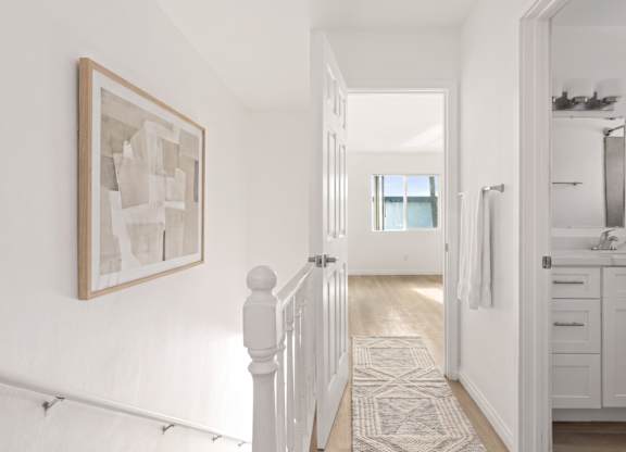 A hallway with a rug and a painting on the wall.