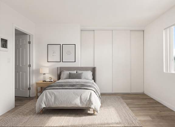 A bedroom with a bed, nightstand, and two picture frames on the wall.