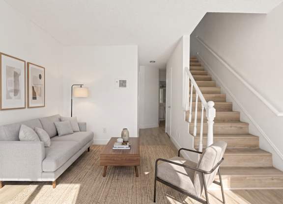 A living room with a couch, chair, and stairs.