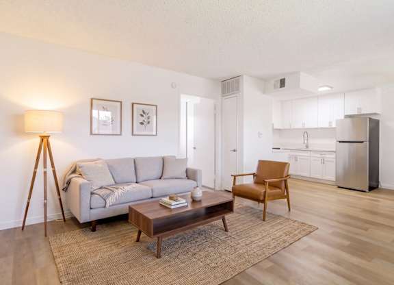 A living room with a grey couch, a wooden coffee table, and a lamp.