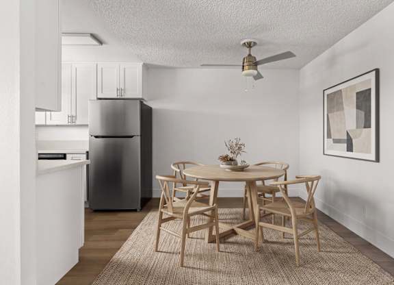 A dining room with a table set for two and a refrigerator in the corner.