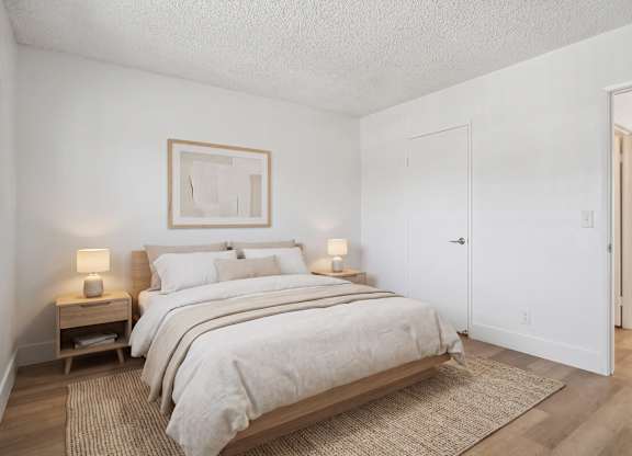 A bedroom with a large bed and two nightstands.