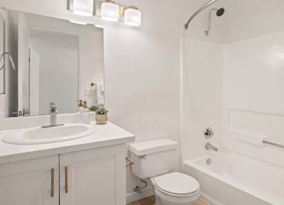 A white bathroom with a toilet, sink, and bathtub.