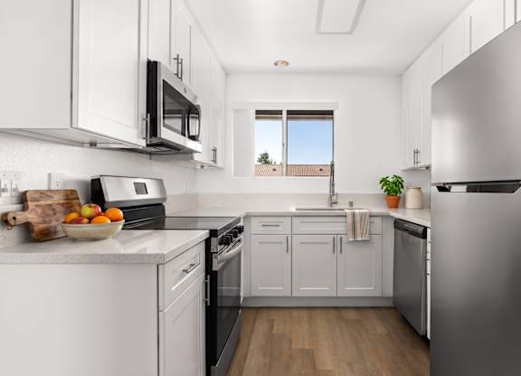 A kitchen with white cabinets and a stainless steel refrigerator.