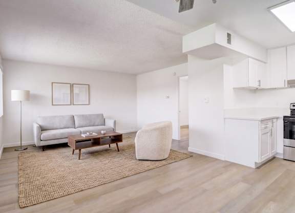 A living room with a grey couch, a white chair, and a wooden coffee table.
