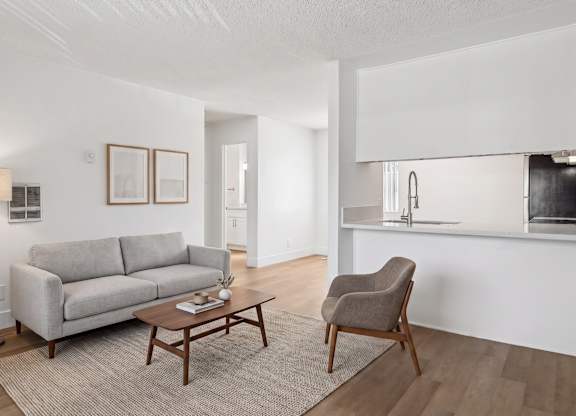 A living room with a grey couch, a brown chair, and a wooden coffee table.