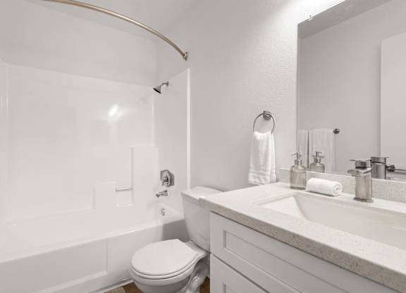 A white bathroom with a toilet, sink, and bathtub.