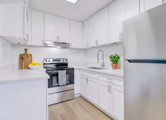 A modern kitchen with white cabinets and a stainless steel refrigerator.