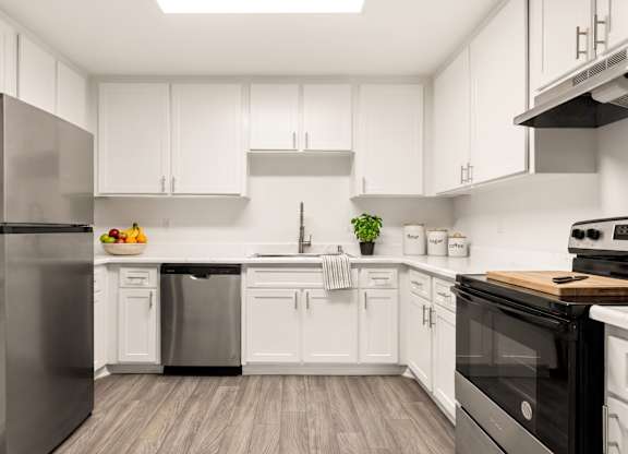 A modern kitchen with white cabinets and stainless steel appliances.