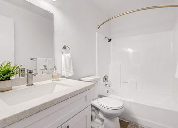 A white bathroom with a toilet, sink, and bathtub.