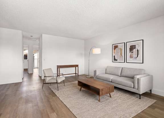 A living room with a grey couch, a wooden coffee table, and a lamp.