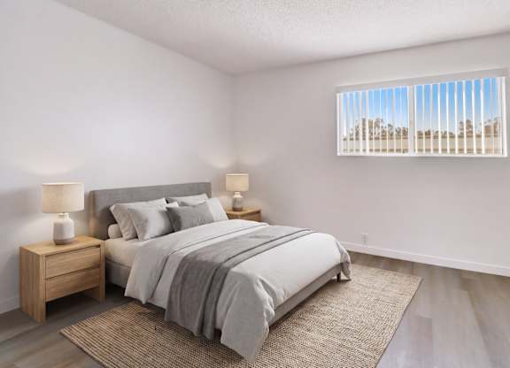 A bedroom with a large bed and a window with blinds.