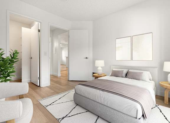 A bedroom with a large bed, a chair, and a potted plant.