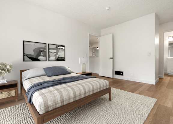 A bedroom with a bed, nightstand, and two framed pictures on the wall.
