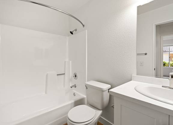 A white bathroom with a toilet, sink, and bathtub.