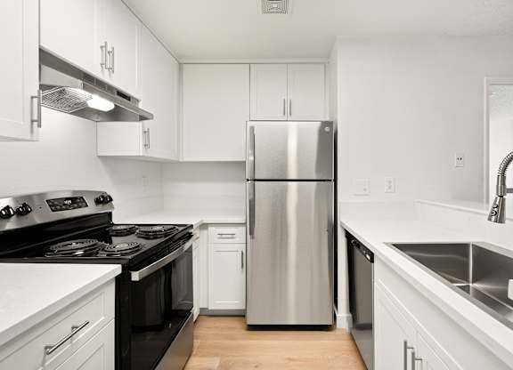 A modern kitchen with a stainless steel refrigerator and black countertops.
