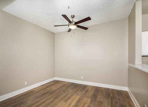 A room with a ceiling fan and wooden flooring.