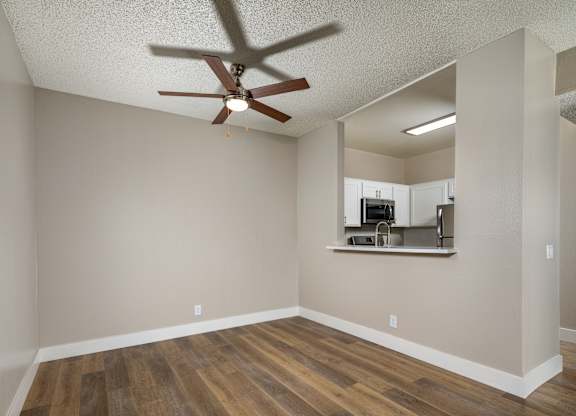 A room with a ceiling fan and wooden flooring.