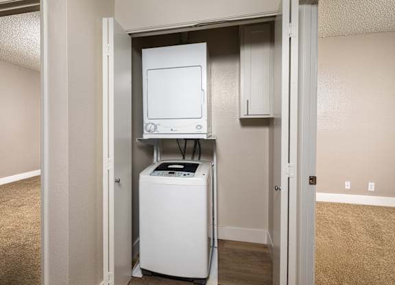 A white dryer and washer are in a small utility closet.