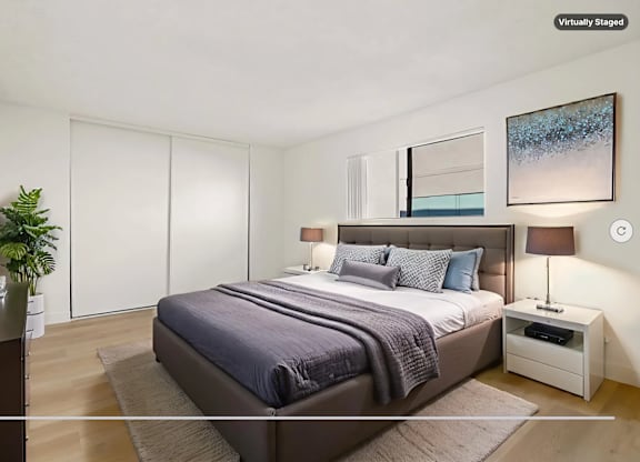 A bedroom with a large bed and a plant on the side table.