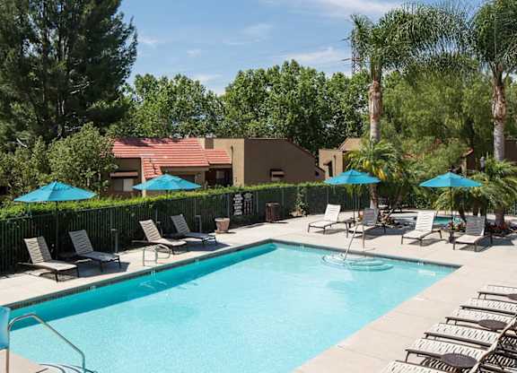 A large swimming pool surrounded by lounge chairs and umbrellas.