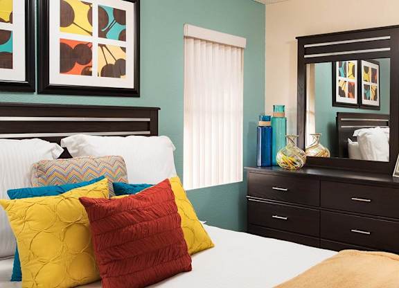A bedroom with a bed, dresser, and mirror.