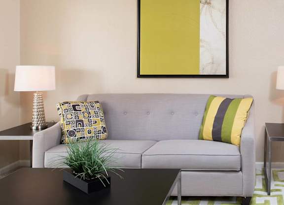 A living room with a grey couch, a black coffee table, and a green rug.
