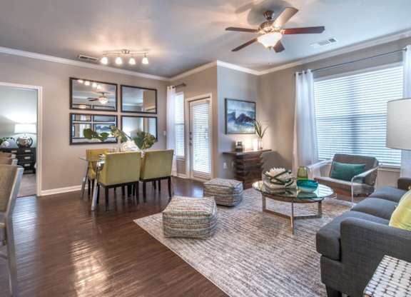 A well-lit living room with a dining area and a ceiling fan.