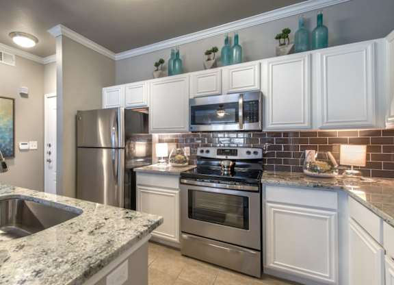 A kitchen with a granite countertop and stainless steel appliances.