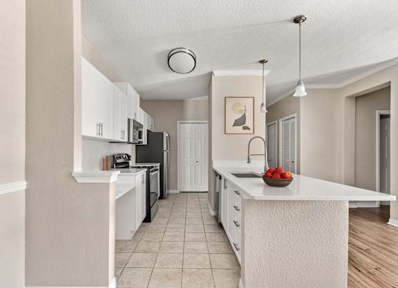 A kitchen with white cabinets and a white island with a bowl of strawberries on it.