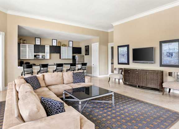A living room with a tan couch and a glass coffee table.