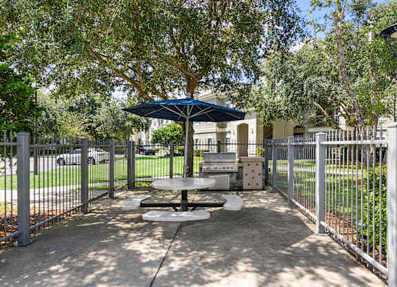 A picnic table is surrounded by a metal fence in a park.