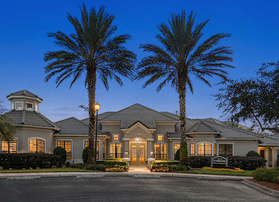 A large house with a tower and palm trees in front.