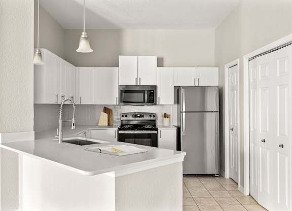 A modern kitchen with white cabinets and appliances.