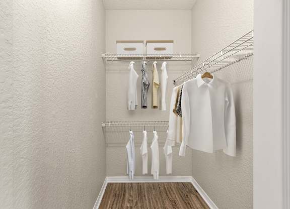 A white closet with clothes hanging on a wire rack.