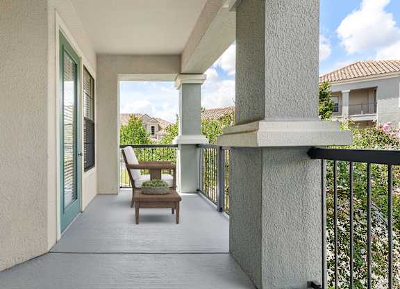 A balcony with a chair and a table with a plant on it.