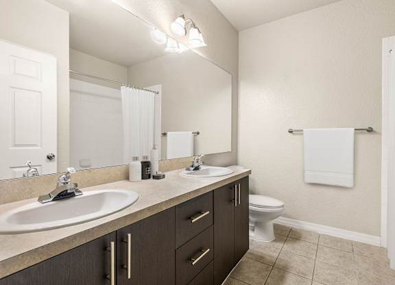 A bathroom with a white sink, toilet, and a mirror.