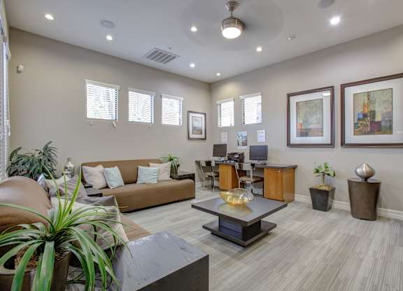 A living room with a brown couch, a coffee table, and a ceiling fan.
